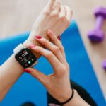 Fitness Trackers - Anonymous sportswoman checking smart watch and sitting on mat