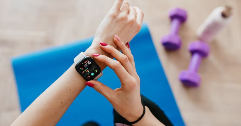 Fitness Trackers - Anonymous sportswoman checking smart watch and sitting on mat