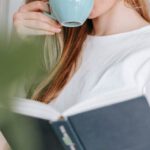 Smart Kitchen - Woman drinking coffee while reading book in kitchen