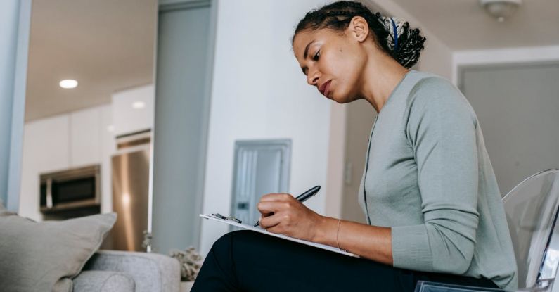 Task Management Apps - Concentrated ethnic female interviewer or psychotherapist taking notes in clipboard