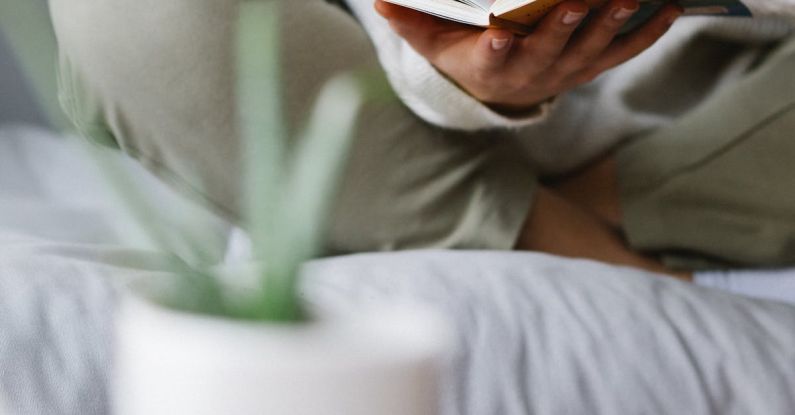 Smart Clothing - Faceless woman reading book on comfortable bed at home