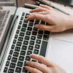 Digital Portfolios - From above of unrecognizable woman sitting at table and typing on keyboard of computer during remote work in modern workspace