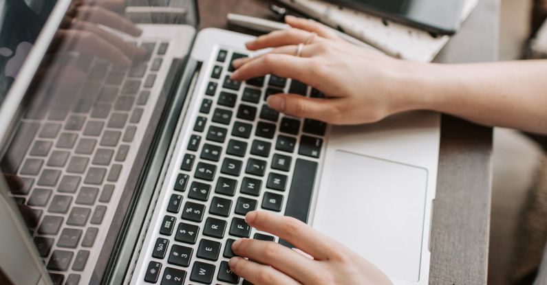 Digital Portfolios - From above of unrecognizable woman sitting at table and typing on keyboard of computer during remote work in modern workspace