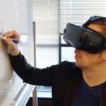 Virtual Reality - Person Wearing Black Vr Box Writing On White Board