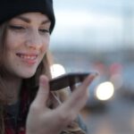 Travel Apps - Joyful young woman phoning on street in evening