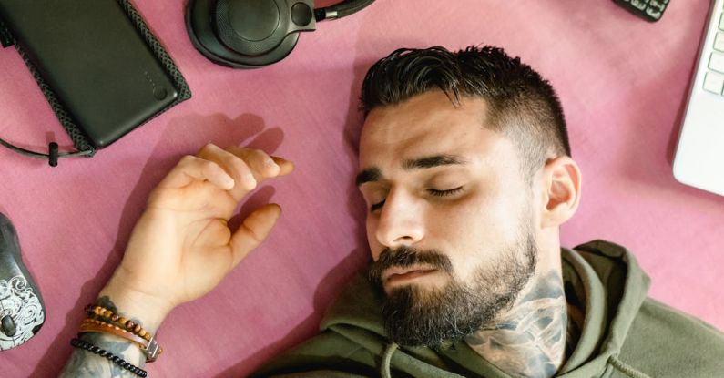 Solar-Powered Gadgets - A Man with Hoodie Jacket Lying Beside the Gadgets